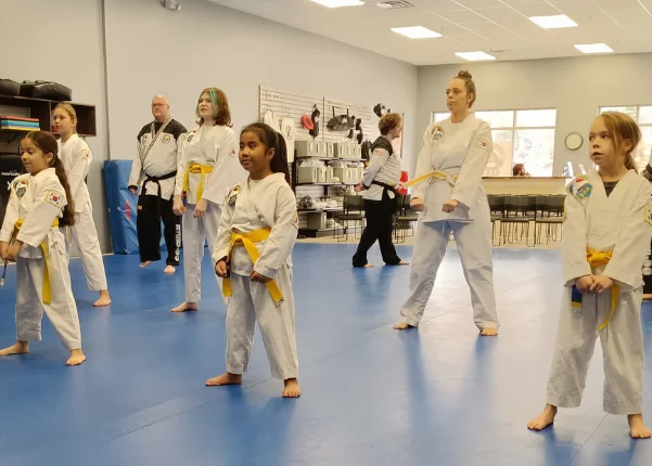 Children and adults in white martial arts uniforms training